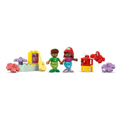 Two colorful LEGO® DUPLO® mermaid figures, Ariel and a friend, holding hands among vibrant underwater-themed accessories including a guitar, flowers, and a friendly crab.