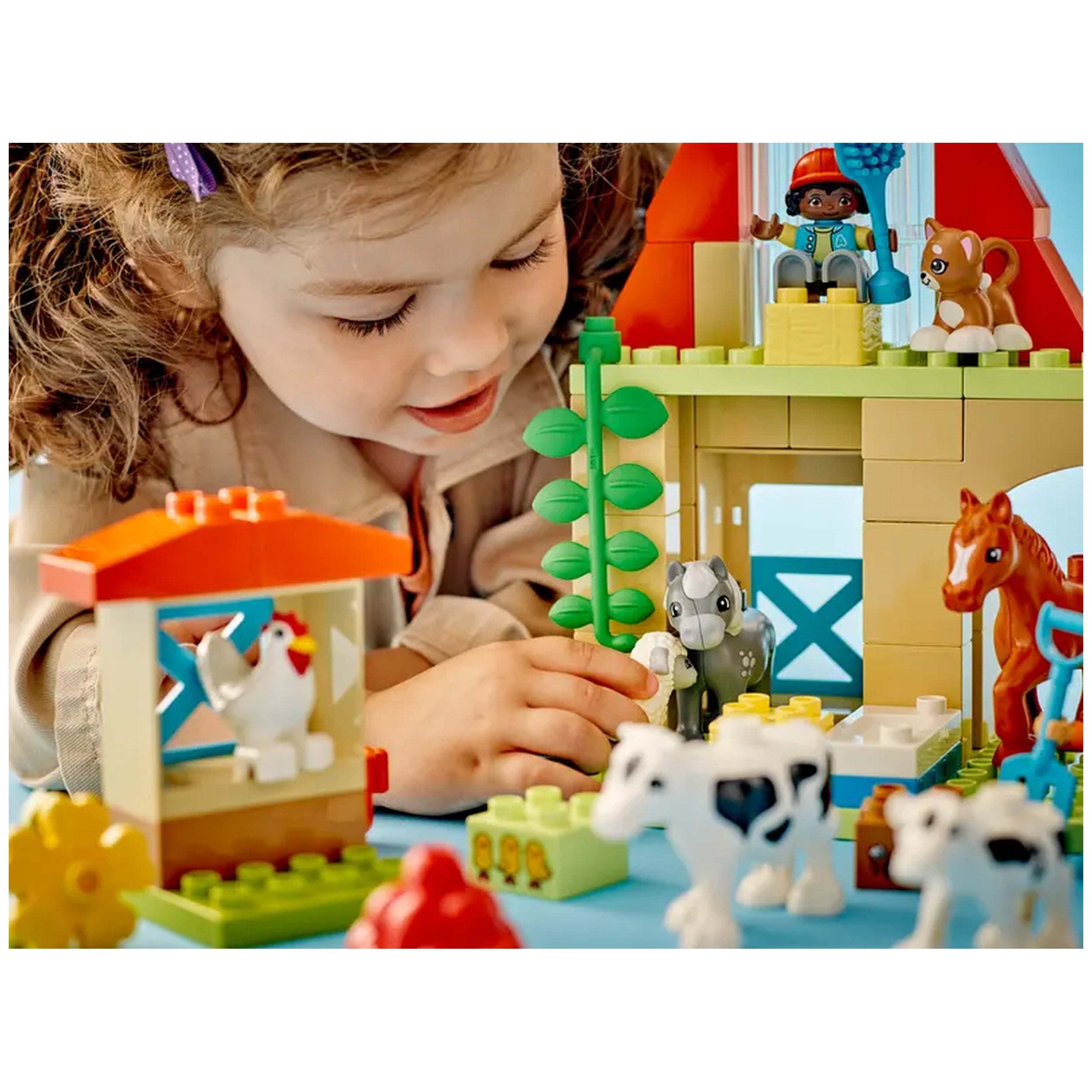 A young child engaging with the LEGO® DUPLO® Caring for Animals at the Farm set, featuring a vibrant farmhouse, animals, and play figures, promoting imaginative play.