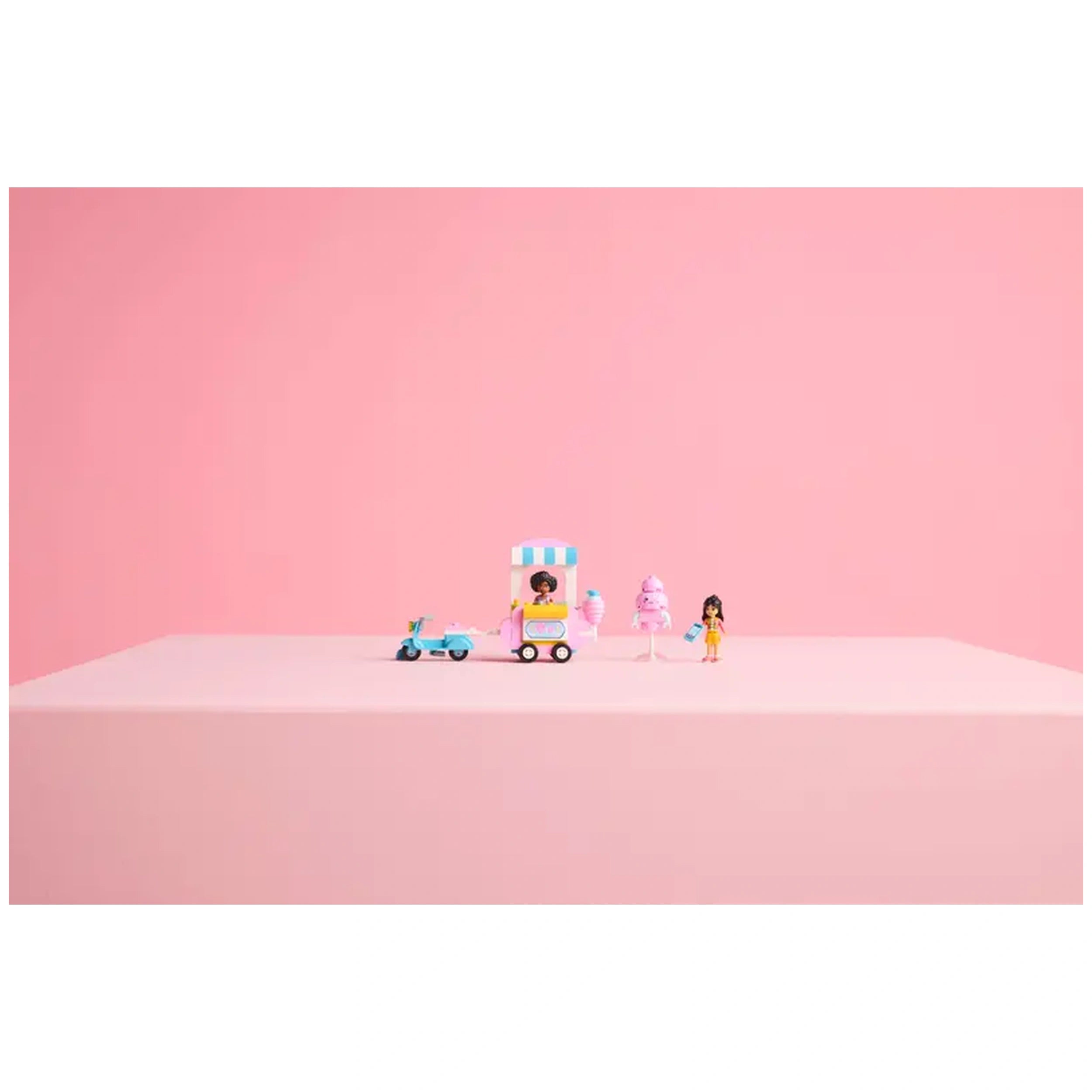 LEGO Friends cotton candy stand set featuring two minifigures, a pink food cart, a scooter, and cotton candy accessories on a pink background.