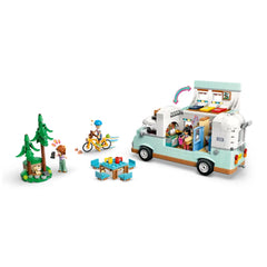 LEGO Friends camper van set featuring a cheerful camper, three minidolls, a bicycle, and forest scene with trees and a ferret figure.