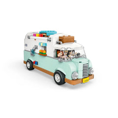 LEGO Friends Friendship Camper Van in light blue with orange accents, featuring two minidolls in the front seats and colorful accessories on the roof.