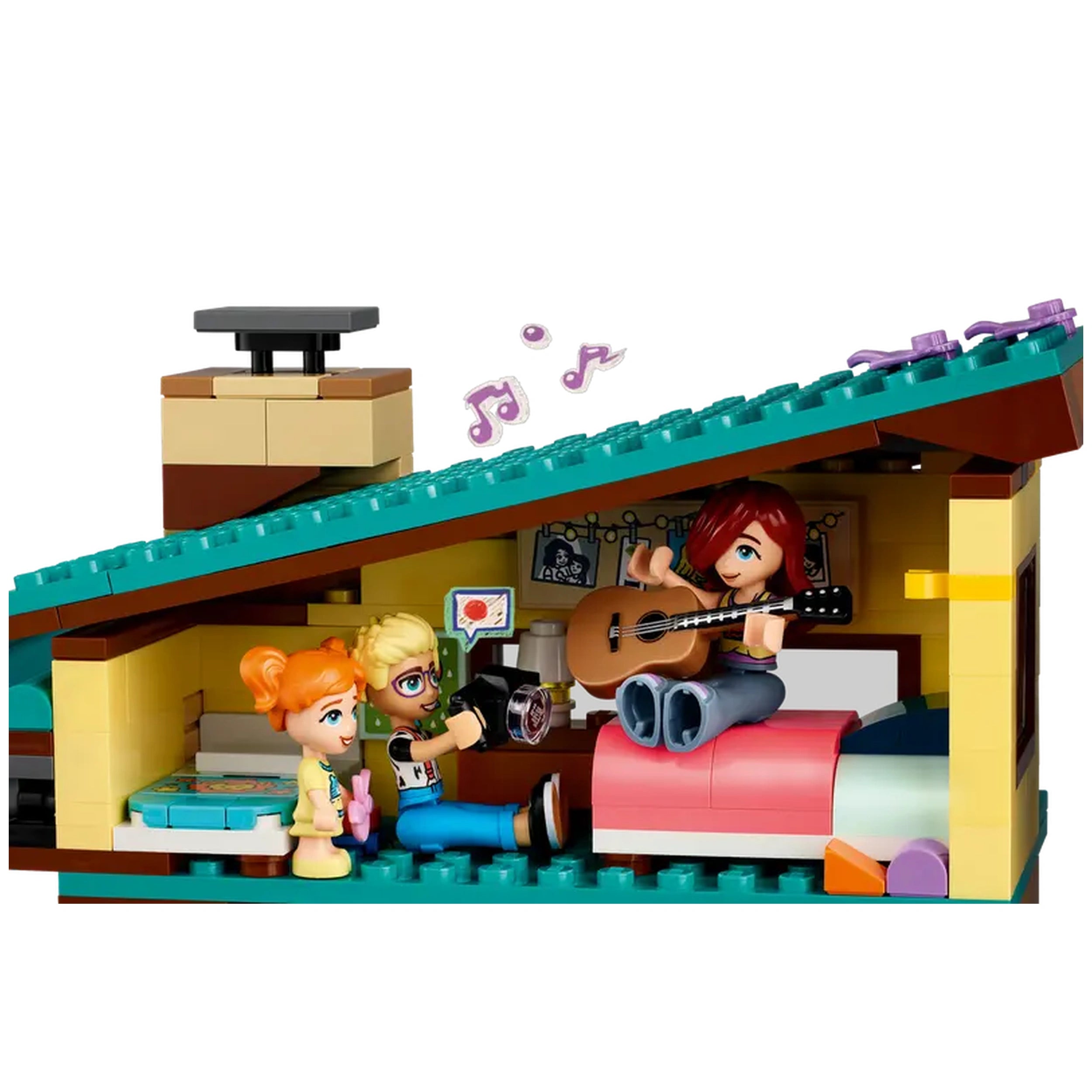 A colorful, LEGO® Friends interior scene featuring three mini-dolls: one playing guitar on a bed, another with a camera, and a third holding a microphone, surrounded by detailed furniture and music notes.