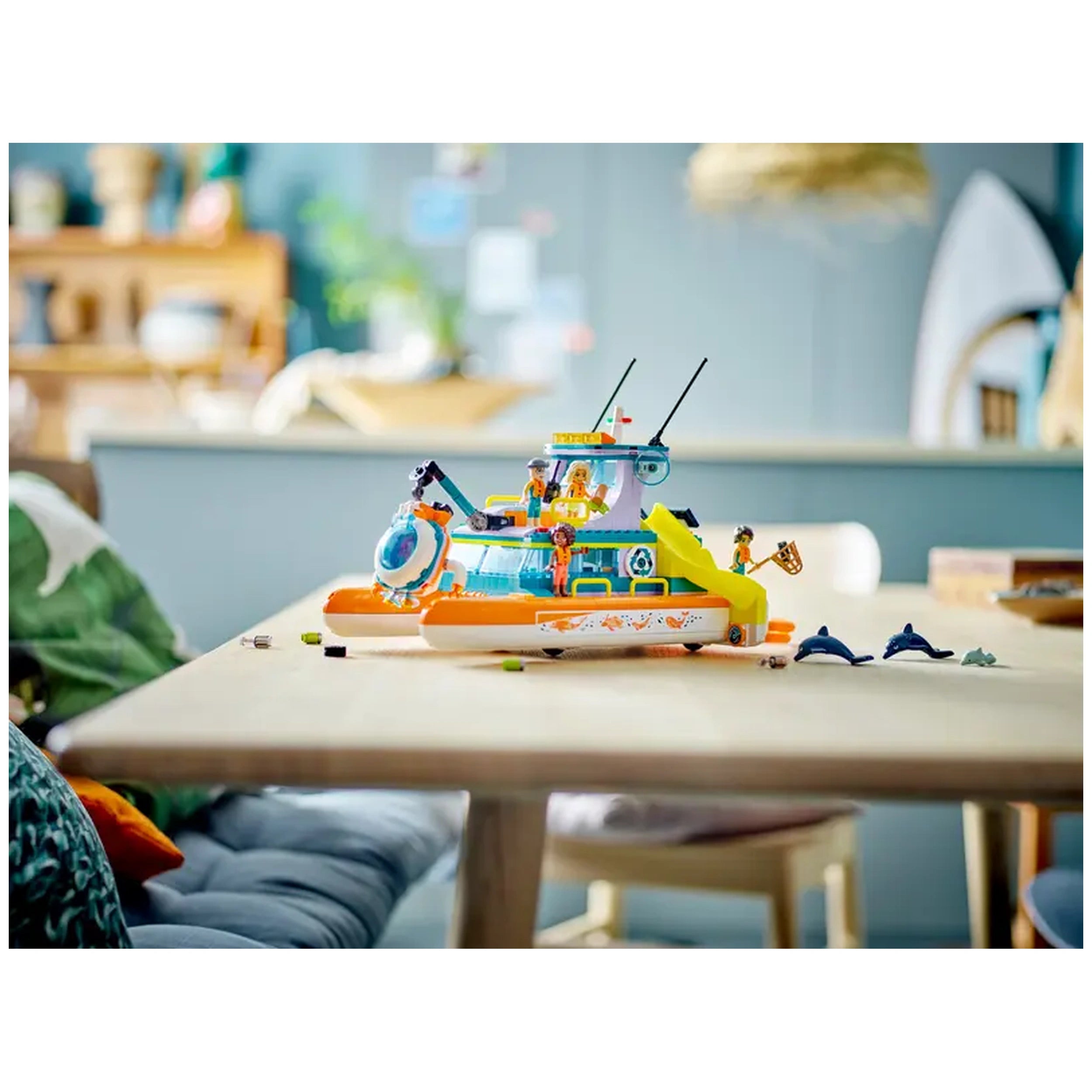 Colorful LEGO® Friends Sea Rescue Boat set displayed on a wooden table, featuring characters, a slide, and toy dolphins.