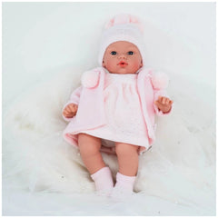 Koke doll in pink duffle coat and hat, lying on soft white fabric, showcasing realistic features and blue eyes.
