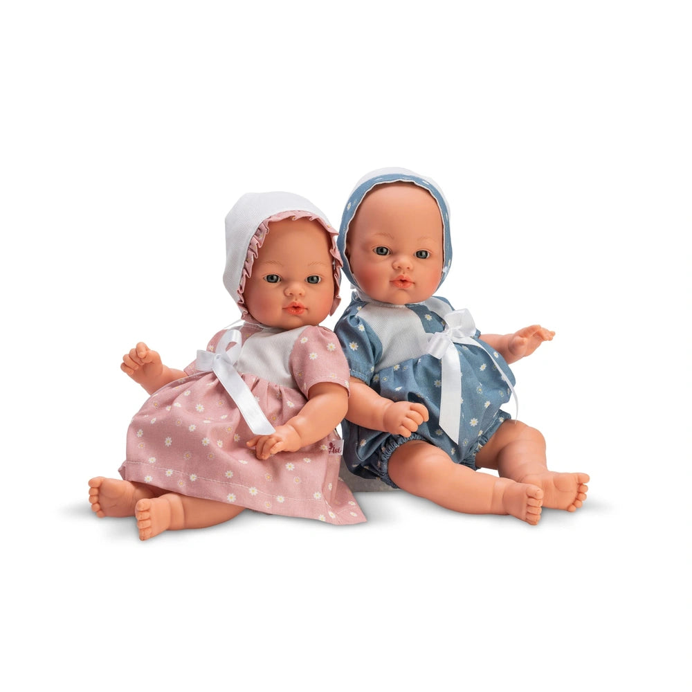 Two ASI Dolls from the Koke Ranita Daisy Collection, one in pink, one in blue, wearing matching bonnets, seated side by side.