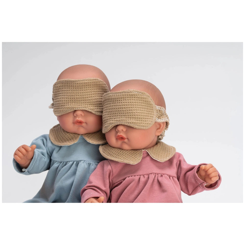 Two ASI Dolls wearing blue and pink pajamas with beige sleep masks, sitting side by side.