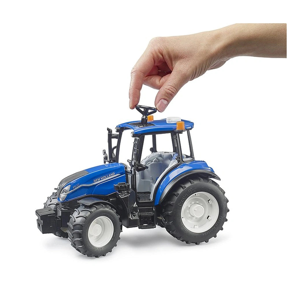 Hand interacting with a blue New Holland T5.120 toy tractor featuring realistic details and rugged tires.