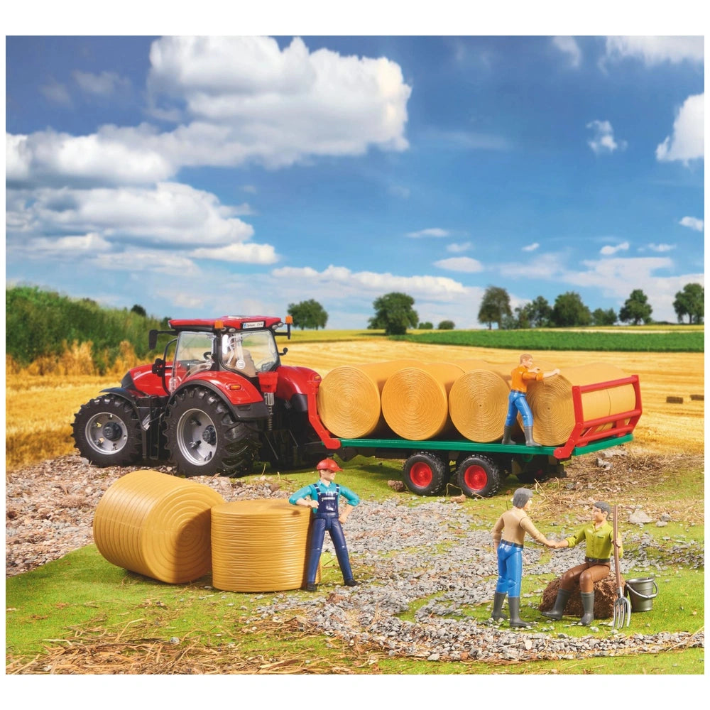 Toy red tractor with bale transport trailer, carrying yellow round bales on a farm. Miniature figures in work scene.