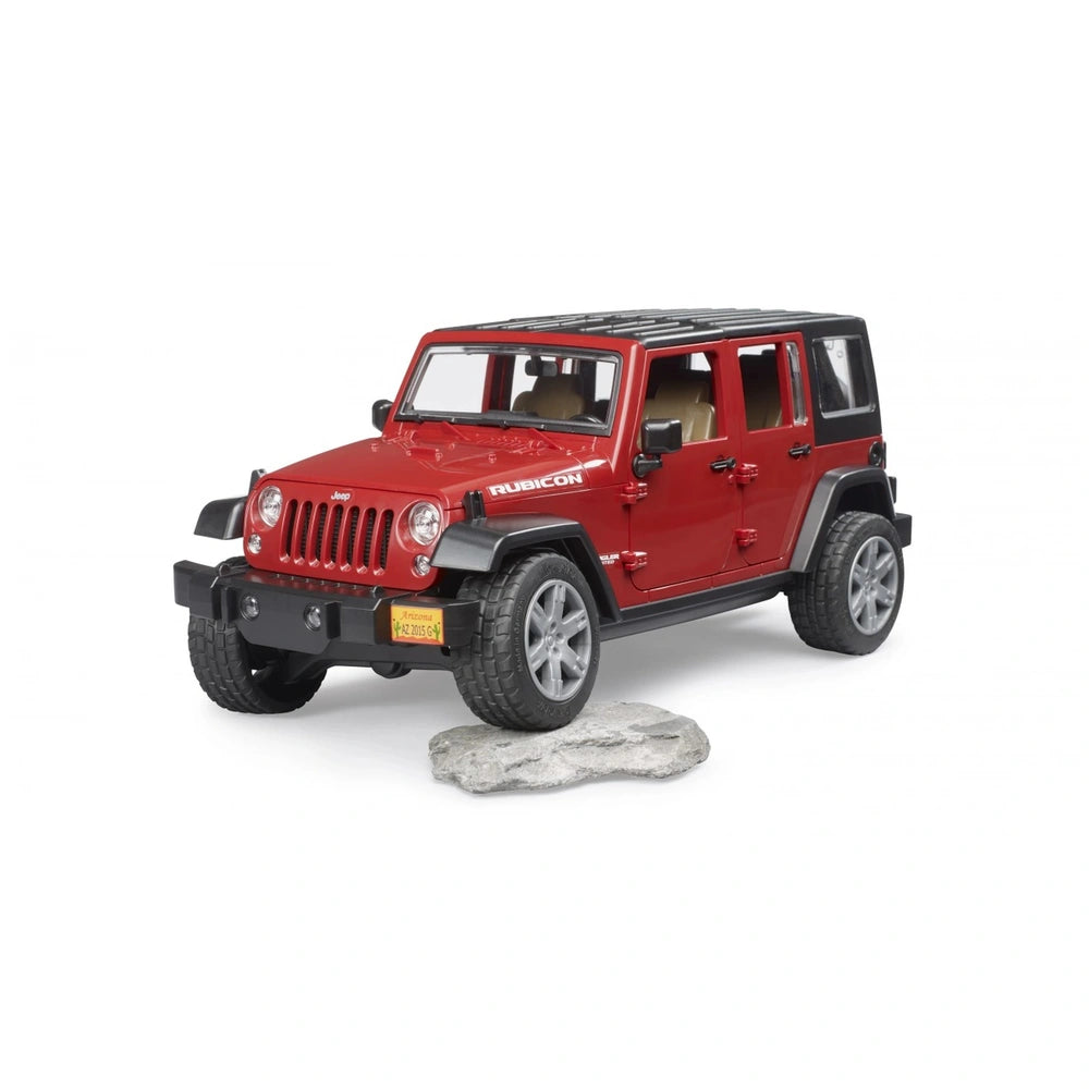 Red Bruder Jeep Wrangler Rubicon model on rocky terrain, featuring realistic details and off-road tires.