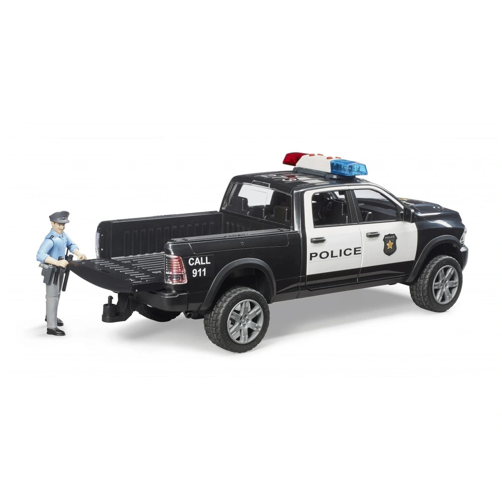 Bruder RAM 2500 black and white police truck toy with officer figurine by the tailgate.