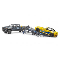 Bruder Ram Power Wagon towing yellow Roadster with racing decals, accompanied by a figure in a racing suit.