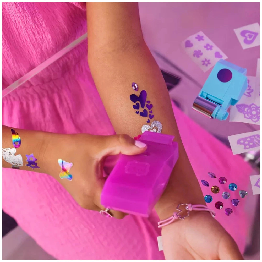 Cool Maker Shimmer Me Body Art Set showcases vibrant temporary tattoos on a person's arm, adorned with hearts and stars.