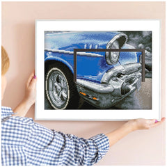 Diamond Dotz 50s Classic displayed in a black frame on a light pink wall, held by a person in a plaid shirt with painted nail