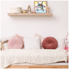 DIAMOND DOTZ Dotzies U baby diamond painting displayed on a wooden shelf with a stuffed animal and decorative pillows.