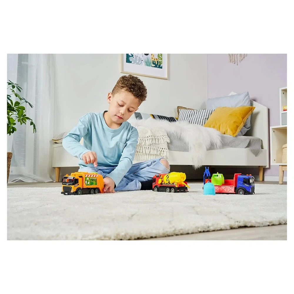 Dickie Toys City Truck in a lifestyle scene with a young boy holding a plastic truck on a light-colored carpet.