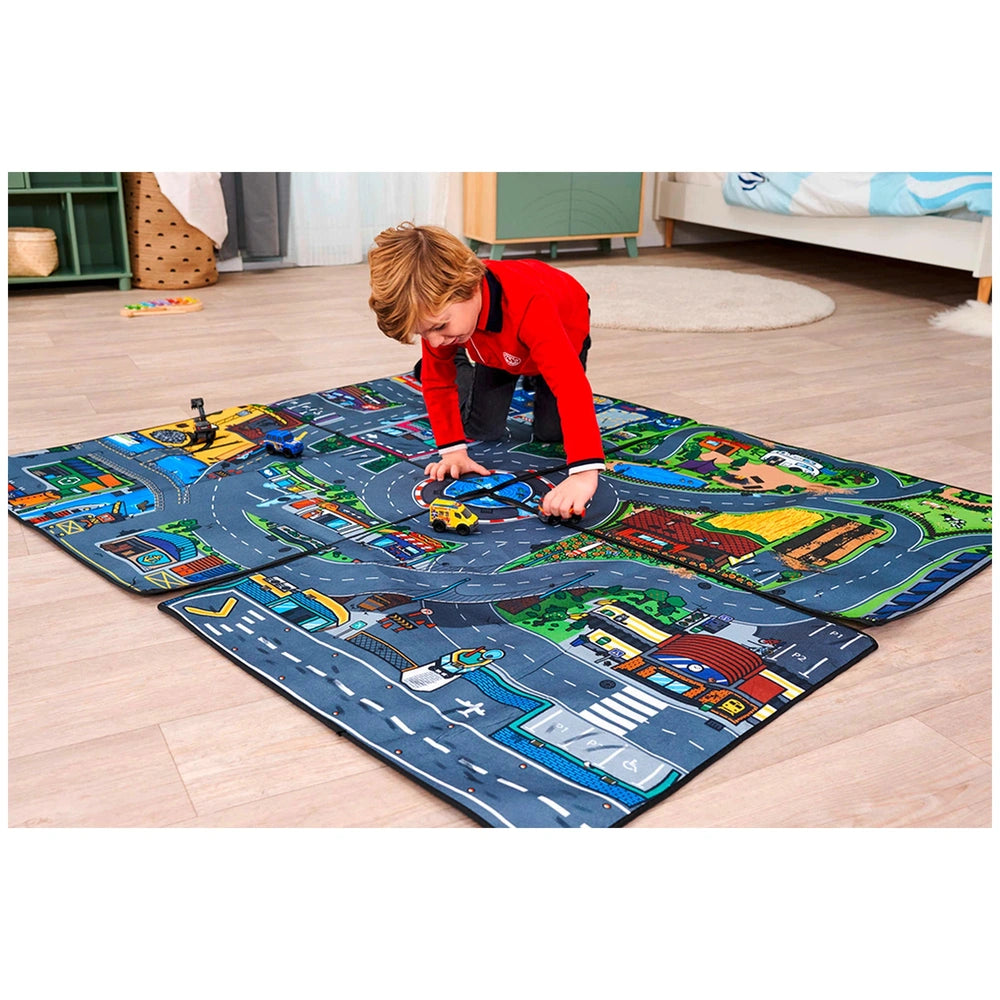 Dickie Playmat features a colorful road map design with vehicles, on light hardwood flooring, as a child plays in red attire.
