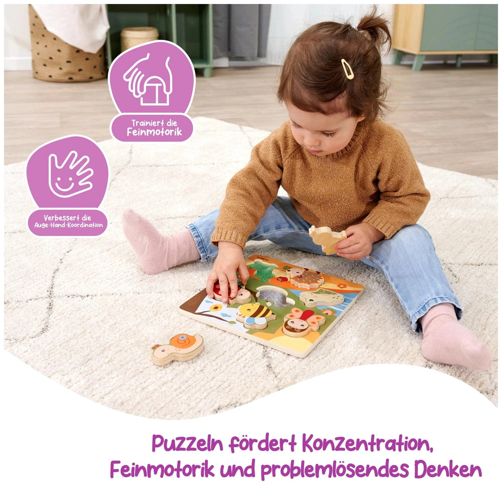 A child in a brown sweater and blue jeans sits on a white rug, intently reading a colorful childrens book.