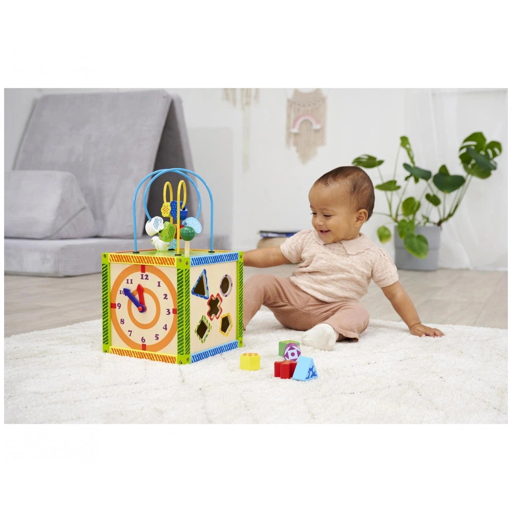 Eichhorn Color Little Play Center engages a smiling child on a plush rug, surrounded by colorful toys in a cozy indoor settin