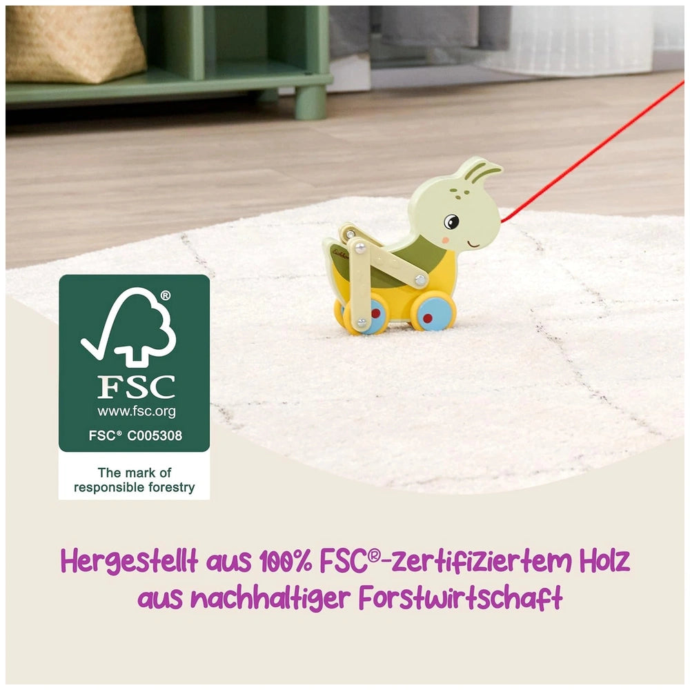 Colorful pulling grasshopper toy with yellow body and green-blue details on a light surface in a neutral-toned room.