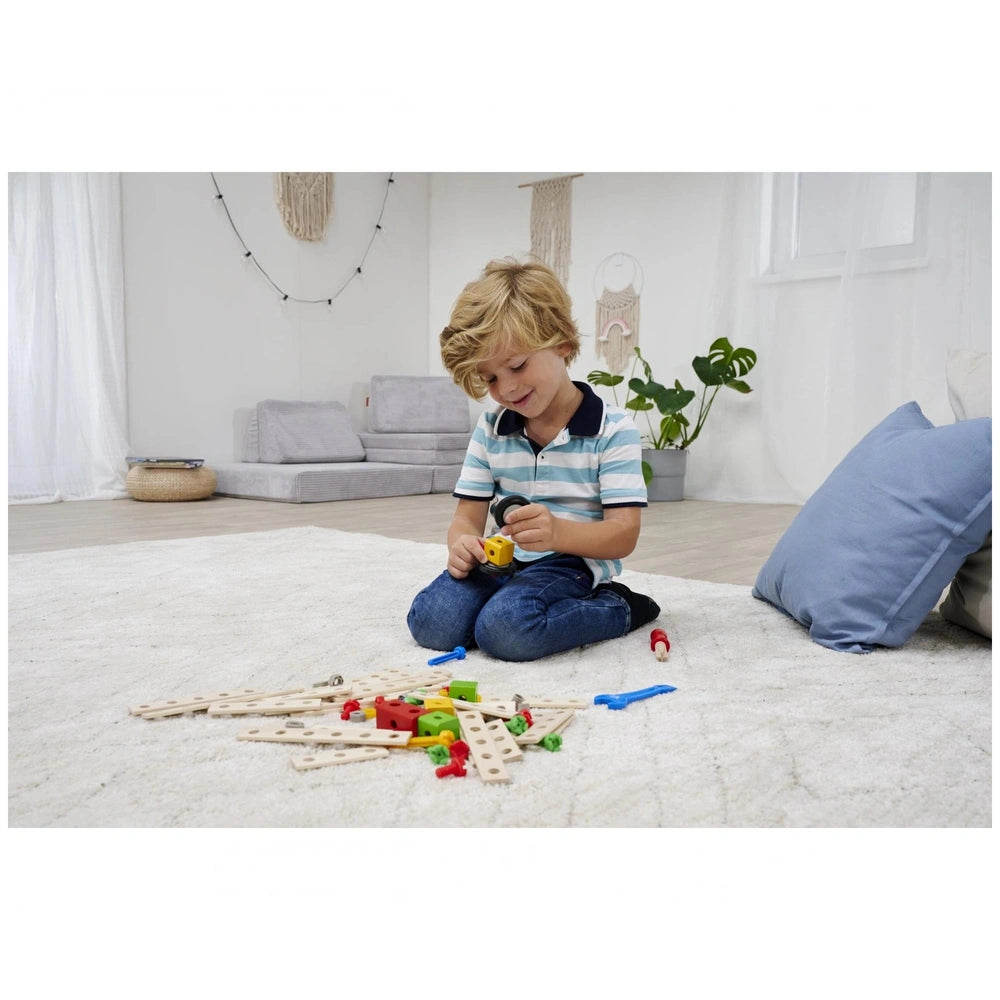 Eichhorn Constructor Expansion Set with 75 pieces, played with by a smiling child on a white carpet in a bright room.