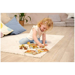 Eichhorn colorful puzzle blocks are scattered around a young girl playing on a white rug over a wooden floor.