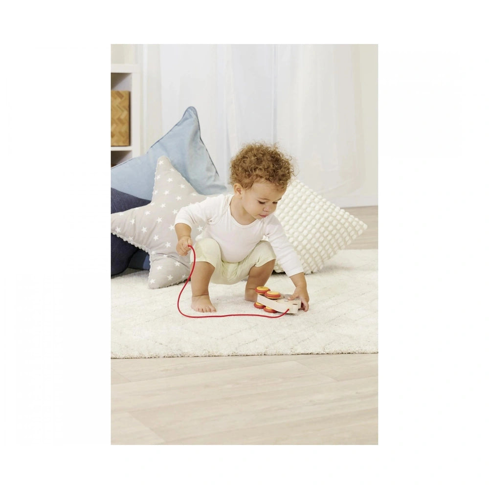 Eichhorn Pull Back Hedgehog with a child playing on a white rug, engaging with toys in a cozy indoor setting.