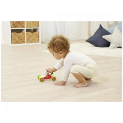 Eichhorn Push Vehicle featuring a child playing with a red tricycle on a wooden floor in a softly lit indoor environment.