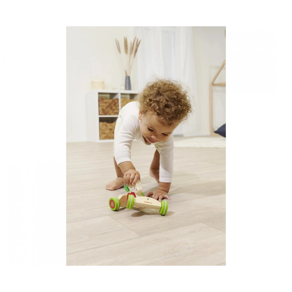 Eichhorn Push Vehicle displayed with a toddler playing on a light wooden floor in a softly lit, neutral-toned room.