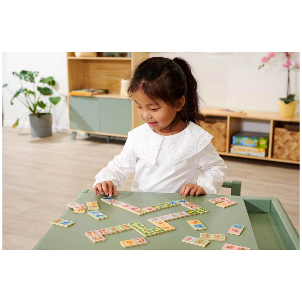 Eichhorn Wooden Domino Game showcased with a girl playing at a light green table in a cozy, well-lit room.