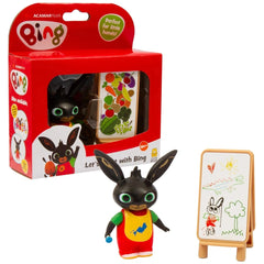 GOLDEN BEAR Lets Paint with Bing toy figure in red and yellow clothing, with green eyes, alongside a whiteboard on a wooden e
