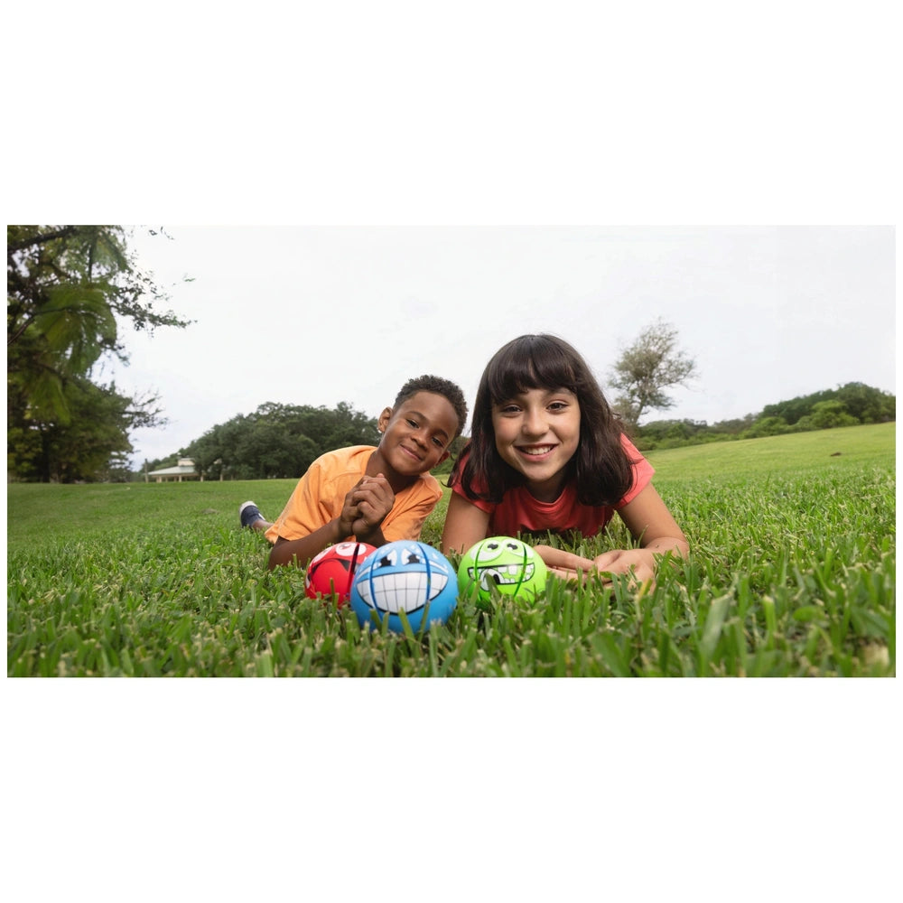 Goliath Wahu Kamuolys Phlat Ball Mini Monsters with two people playing on green grass, one holding a blue and white ball.