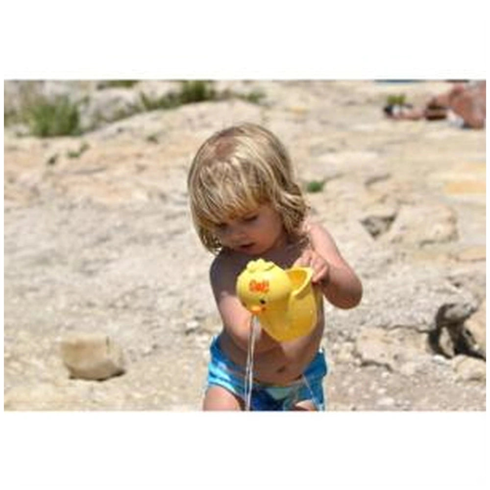 Gowi beach toys displayed in a lifestyle scene with a child in a blue swimsuit holding a yellow toy on sandy ground.