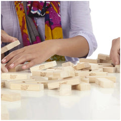 Jenga Family Game with light brown wooden blocks on a colorful patterned cloth table, featuring a hand reaching for a block.