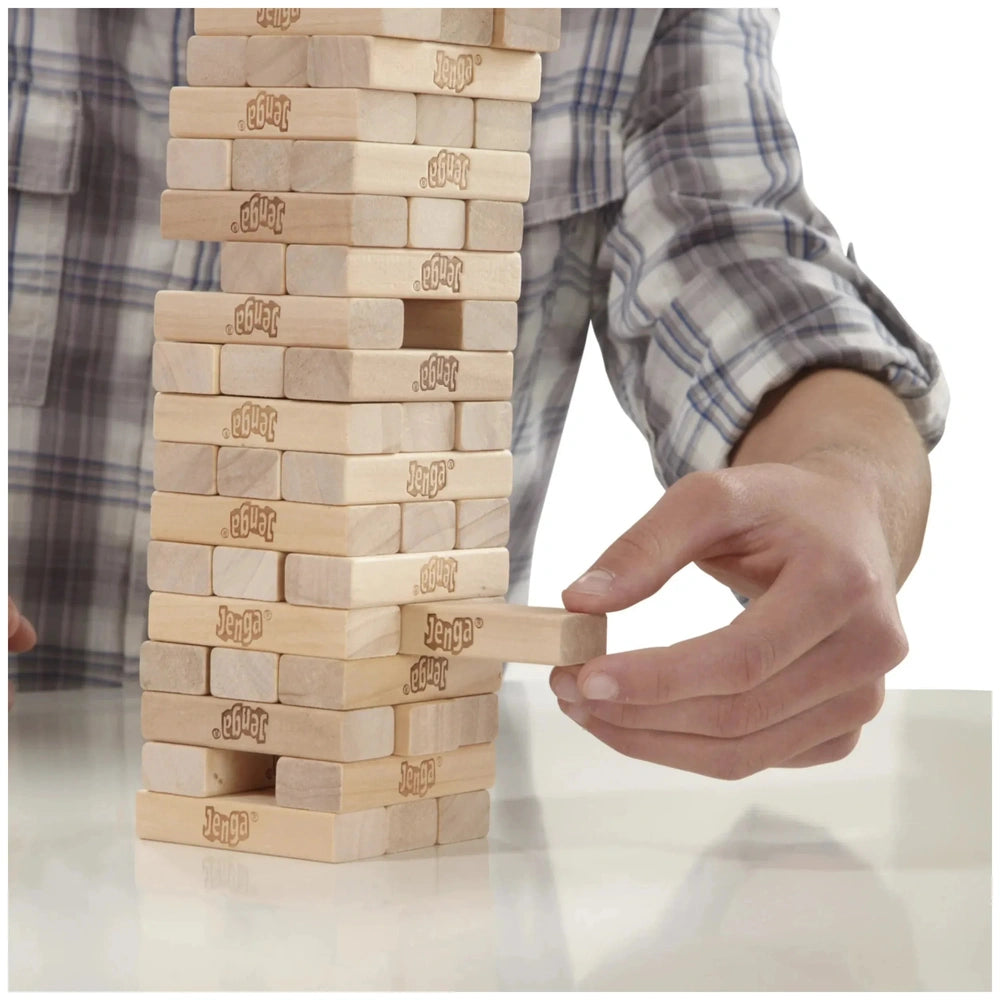 Jenga Family Game features a stack of brown wooden blocks on a white surface, with a hand holding one block.