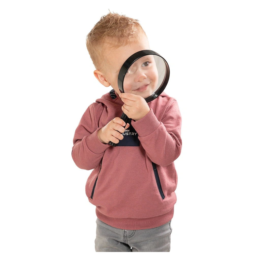 Johntoy Science Explorer Magnifying Glass held by a blonde child with blue eyes, focusing intently on the lens.