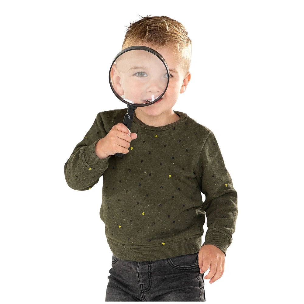 Johntoy Science Explorer Magnifying Glass held by a child with blonde hair, examining objects with curiosity.