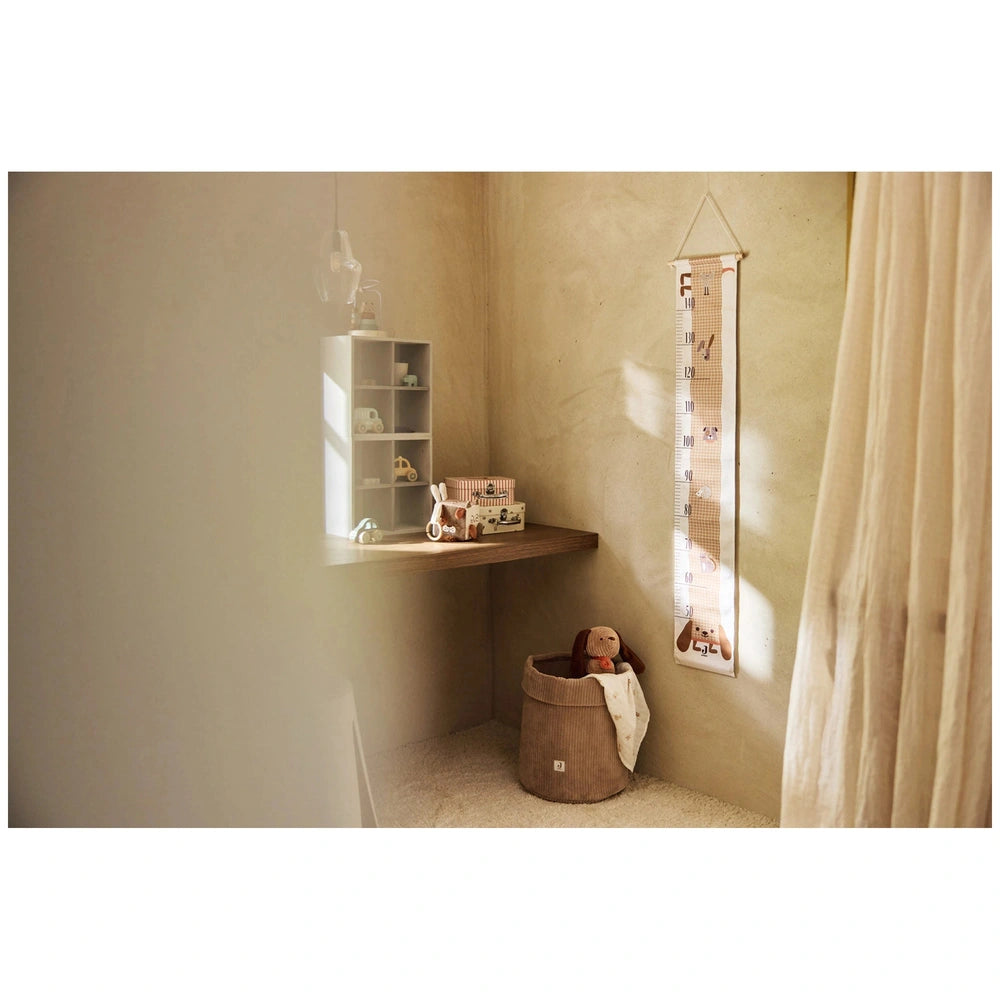Jollein Activity Cube Animal Friends displayed on a white shelf against a beige wall with a brown woven basket nearby.