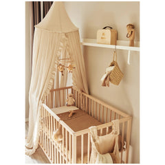 Jollein Musical Hanger features stuffed animals above a brown wooden crib with a white canopy on a beige carpet.