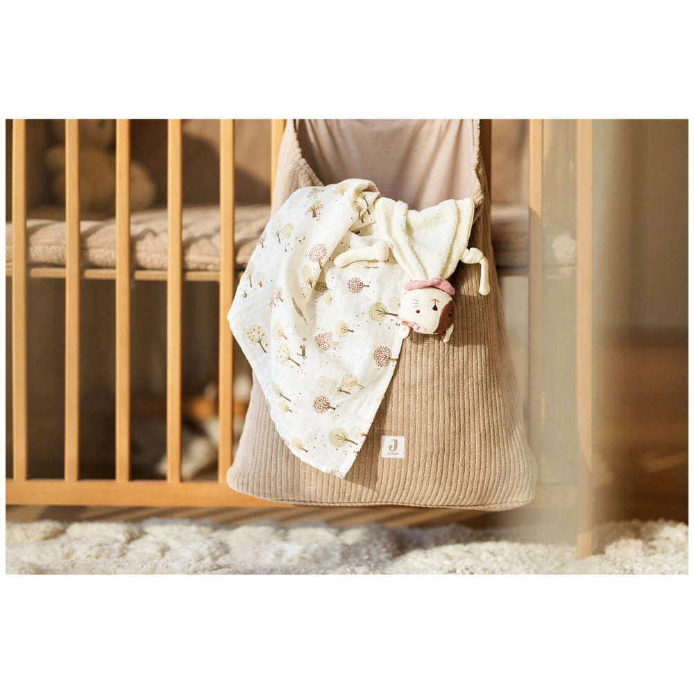 Jollein pacifier cloth Jill on a light beige fabric in a wooden crib with a pink and brown stuffed animal nearby.
