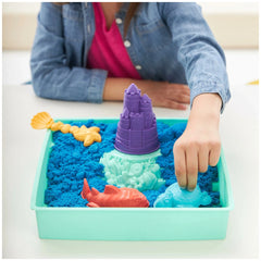 Kinetic Sand Sandbox Set features a blue turtle toy held by a hand over a blue sand-filled tray with a yellow shell and purpl