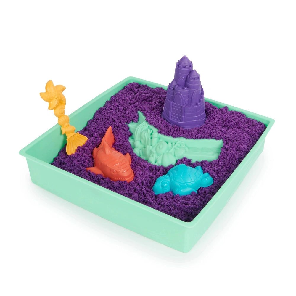 Kinetic Sand Sandbox Set features a light green container filled with purple sand and playful toys: a yellow flower, purple c