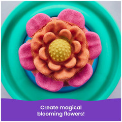 Kinetic Sand Squish Blossom features a vibrant flower-shaped cake in pink and orange on a teal plate, inviting creativity.