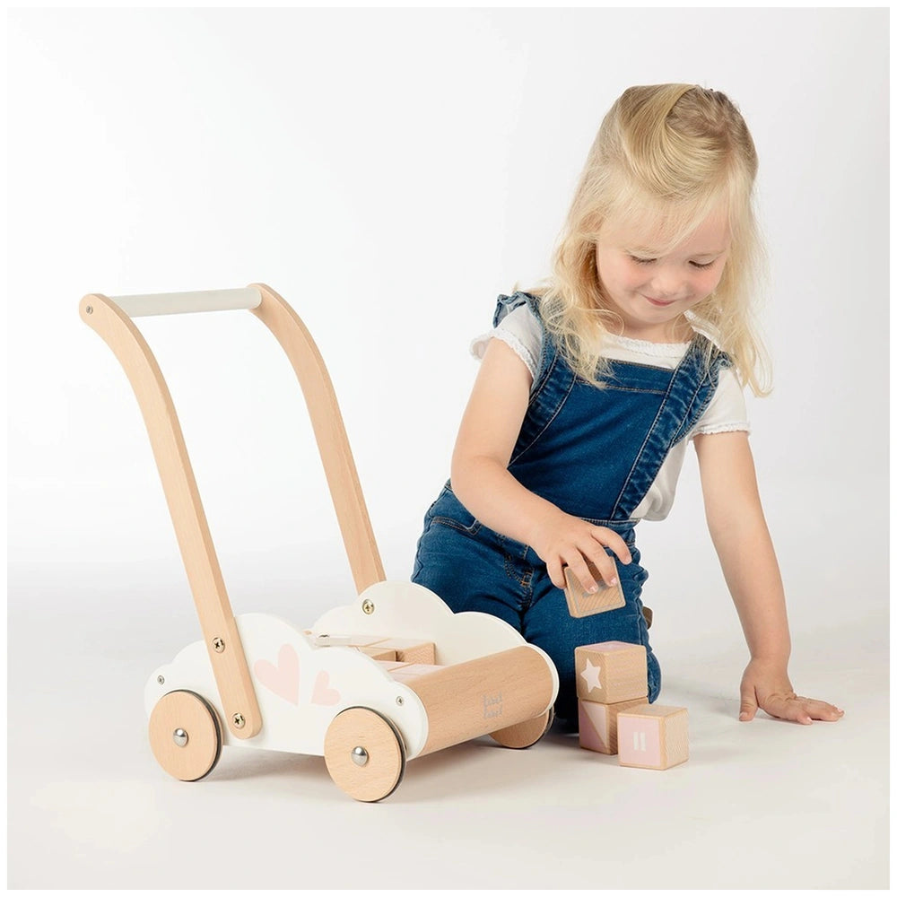 Educational Baby Walker with white body and wooden handle, held by a young girl in blue overalls and white shirt.