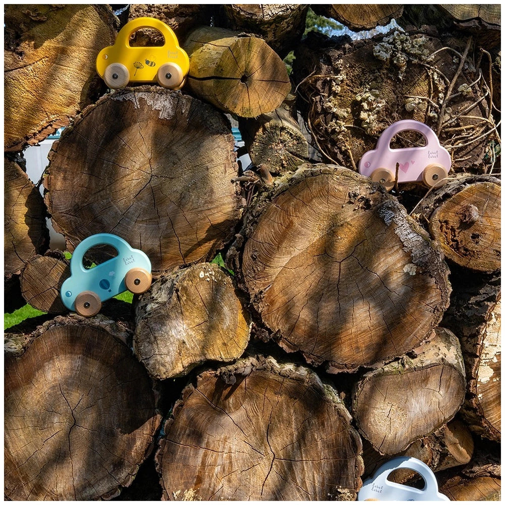 Label-Label Little Car push and pull toys feature a yellow, blue, and pink toy car on wooden logs in a close-up view.