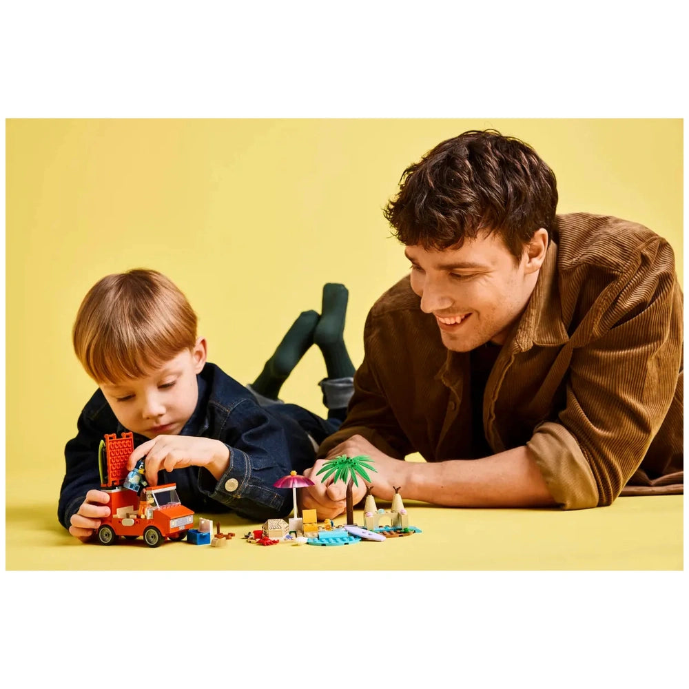 A young boy plays with the LEGO Bluey family car set on a yellow background, while a smiling man leans beside him, engaged in the activity.
