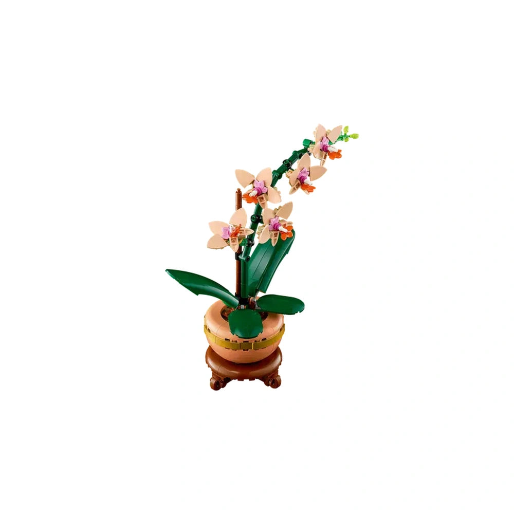 LEGO Mini Orchid construction set featuring five peach blooms, green leaves, and a light terracotta flowerpot on a wooden plinth.