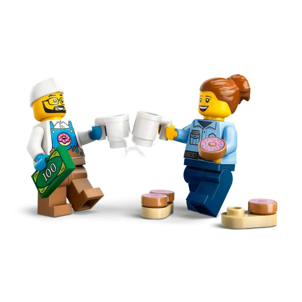 Two LEGO minifigures celebrating with coffee cups, one holding a donut, surrounded by small toy donuts on a white background.