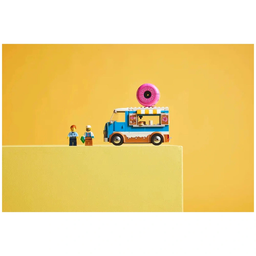 LEGO City Donut Truck with a pink donut on top, accompanied by two mini-figures, set against a bright yellow background.