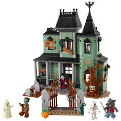 Haunted mansion constructed with green and gray bricks, featuring a detailed graveyard, spooky tree, and four character figures including a ghost, zombie, skeleton, and werewolf, along with an ornate front gate.