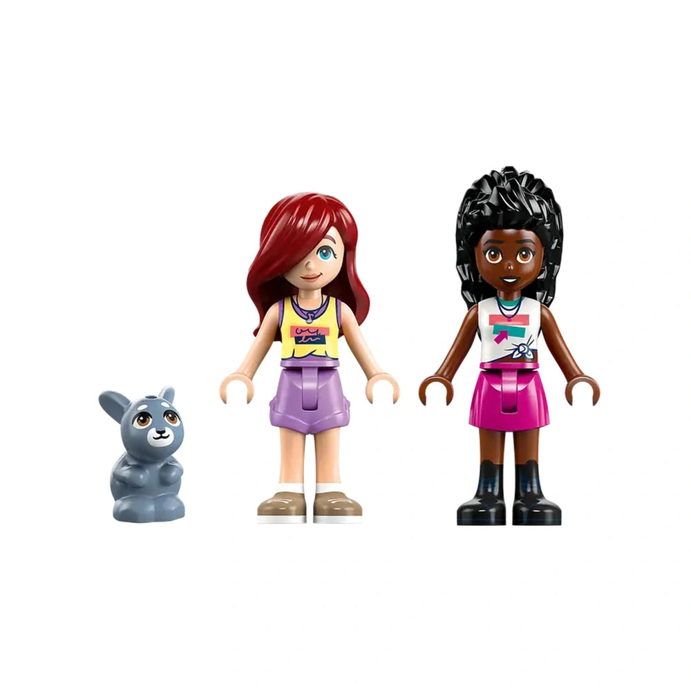 Two minidolls, one with red hair and purple skirt, the other with dark hair and pink skirt, stand beside a small gray bunny figure, all against a white background.